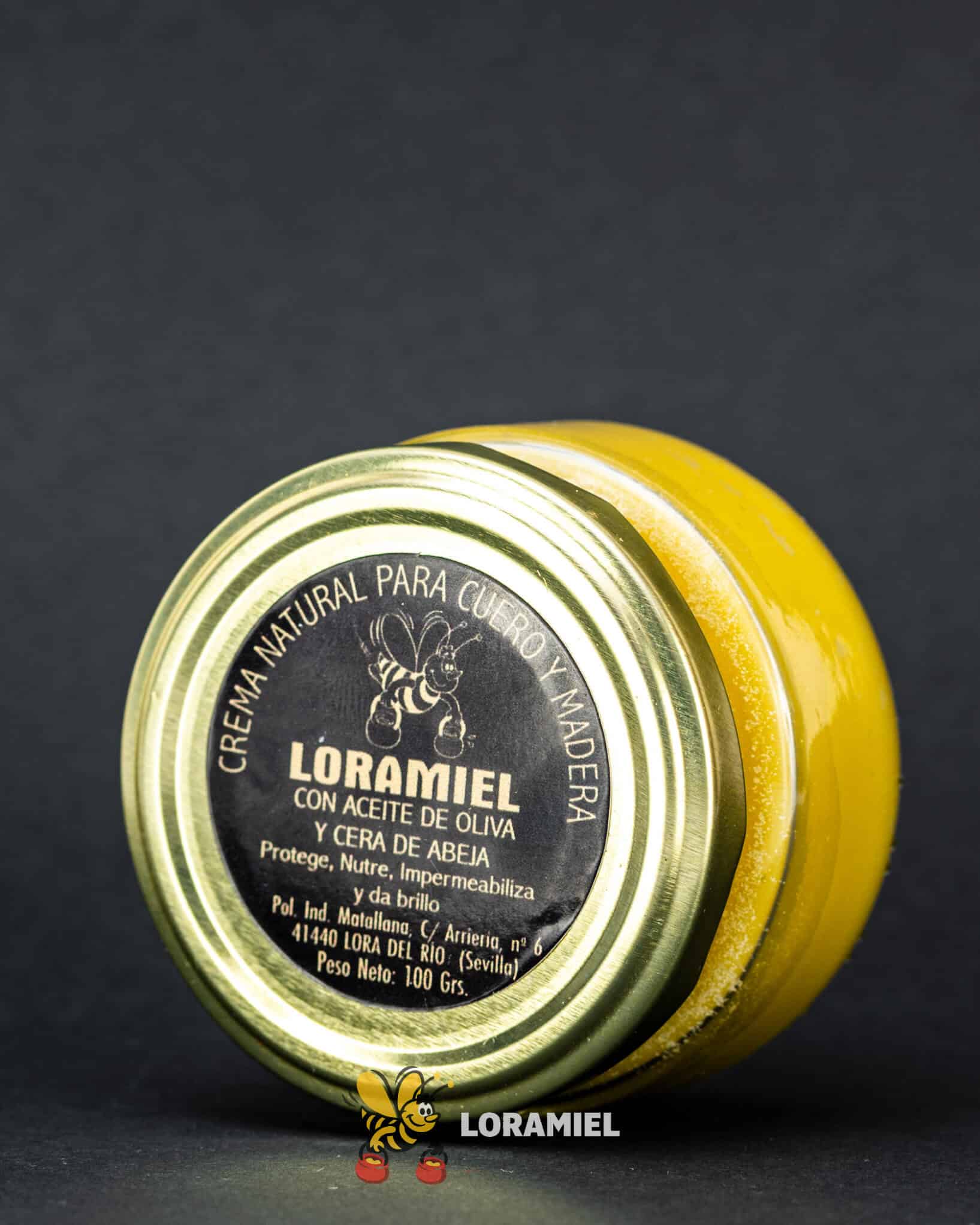 Tarro de crema natural Loramiel con cera de abeja y aceite de oliva para cuidado de cuero y madera sobre fondo oscuro