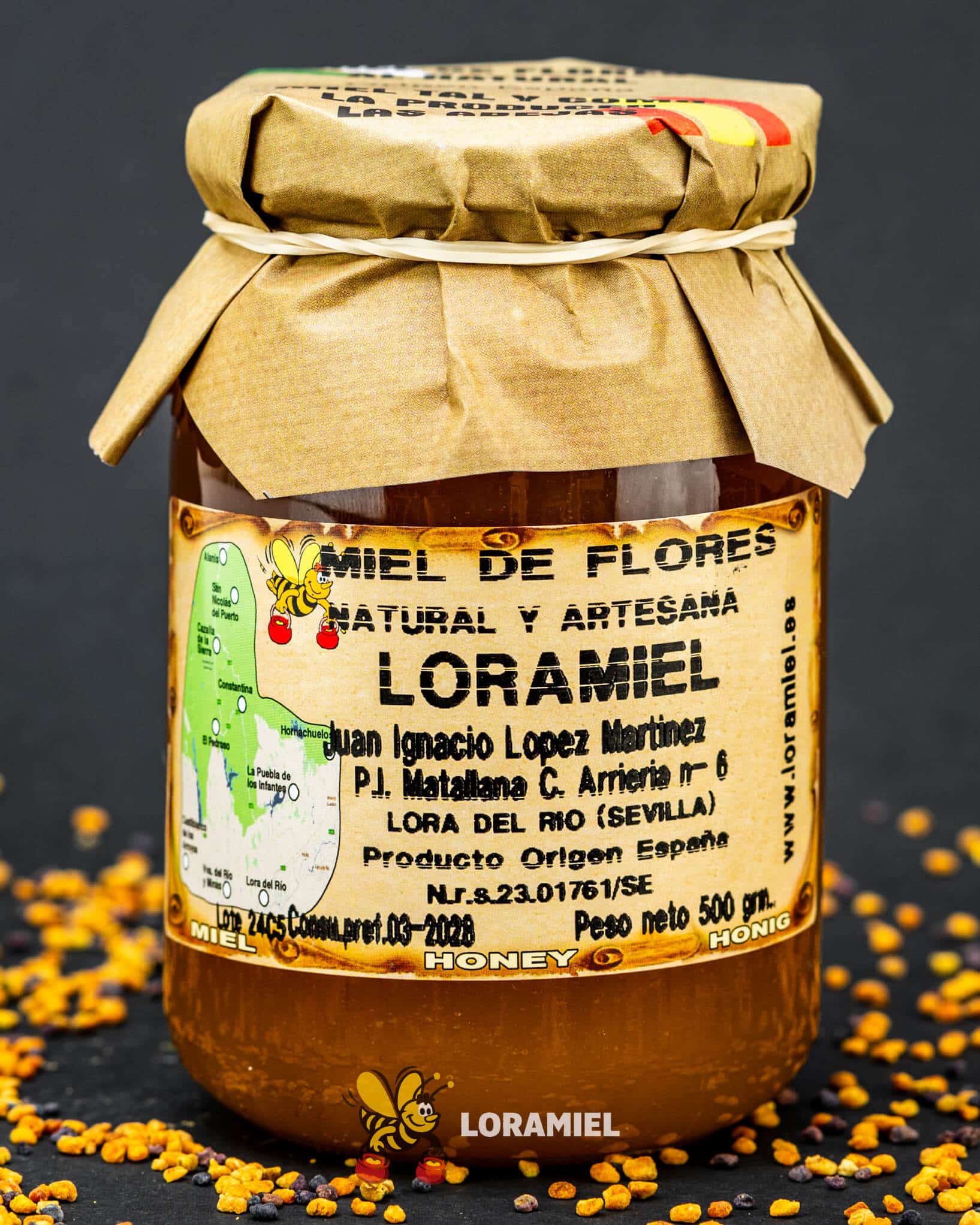 Tarro de miel de flores Loramiel natural y artesanal con tapa de papel sobre fondo oscuro con polen esparcido