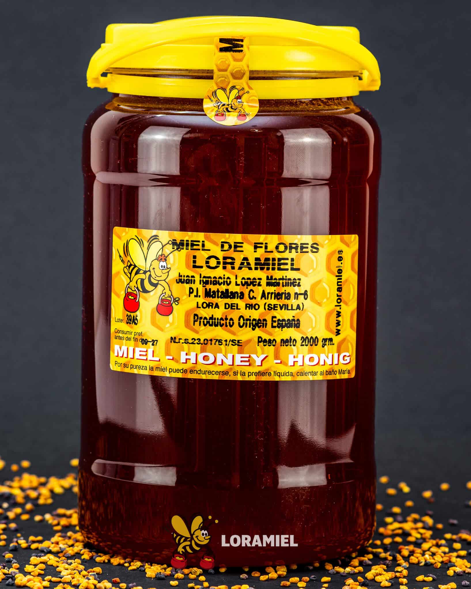 Tarro grande de miel de flores Loramiel de color ámbar oscuro sobre fondo negro con polen, producto natural artesanal de Sevilla