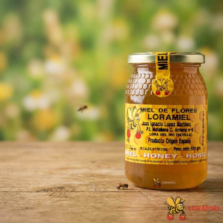 Tarro de miel de flores natural Loramiel sobre mesa de madera con fondo desenfocado de campo y abejas alrededor